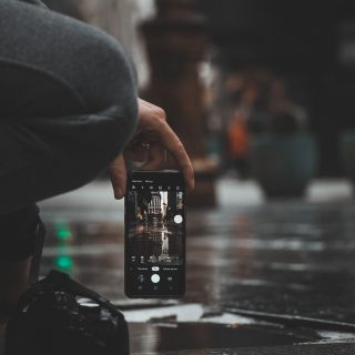运营人员手持手机检查移动端播放效果的特写，背景是明亮的办公环境